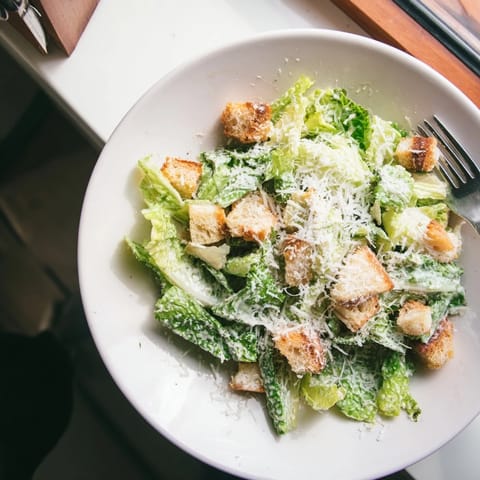 A classic Caesar Salad with crisp romaine, crunchy croutons, and creamy homemade dressing. Freshly grated Parmesan cheese adds savory flavor to this easy side dish.