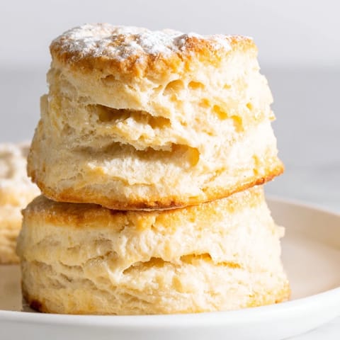 Freshly baked Buttermilk Biscuits served warm with melted butter and honey on a rustic plate.