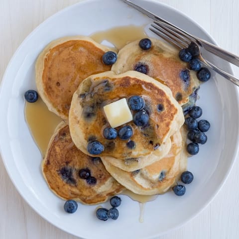 Warm Blueberry Pancakes topped with butter and syrup, a fluffy American breakfast perfect for weekend brunch.