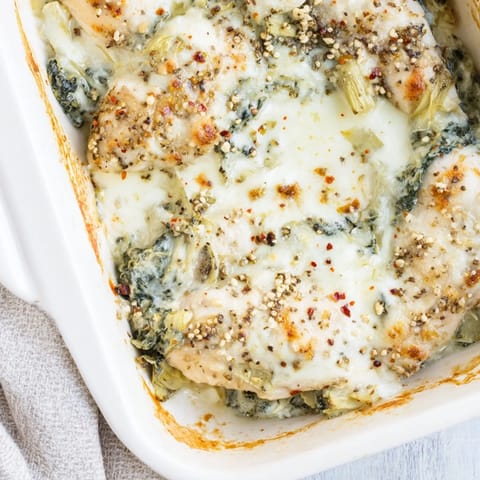 Golden-brown Spinach & Artichoke Chicken Bake fresh from the oven, bubbling with creamy topping and served alongside quinoa.  