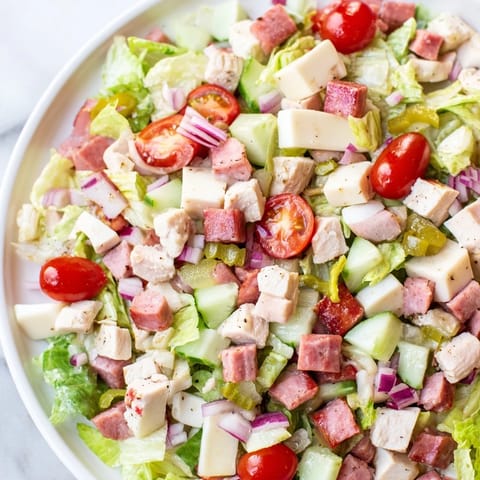 Italian Deli Chopped Chicken Salad served in a white bowl with cherry tomatoes and pepperoncini for a zesty kick.  