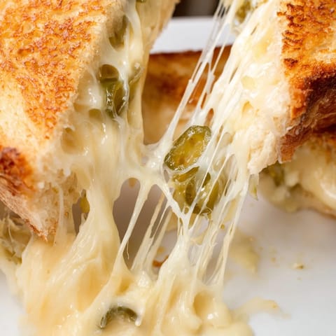 Sizzling Jalapeño Pepper Jack Grilled Cheese in a skillet, featuring gooey melted cheese and spicy jalapeño slices peeking out.