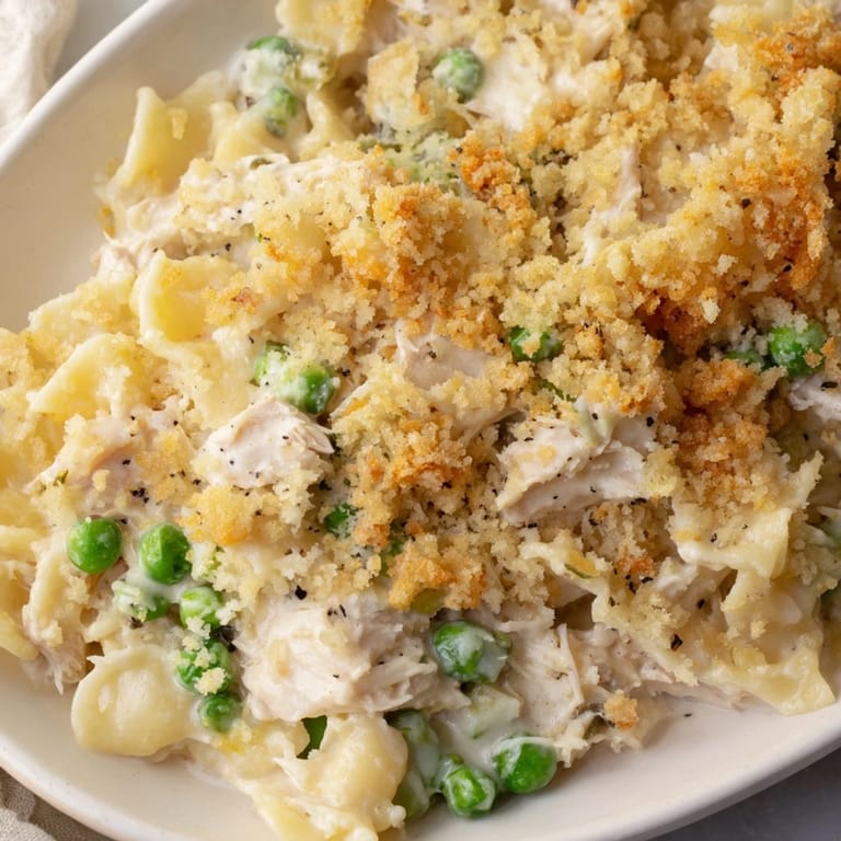 Freshly baked Tuna Casserole with bubbly cheddar sauce, tuna, and pasta, served in dish.