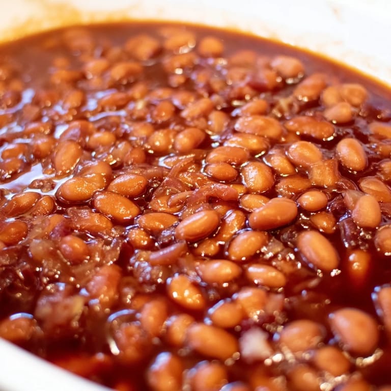 Golden-brown baked beans bubbling in a Dutch oven, finished with a sprinkle of fresh parsley for garnish.