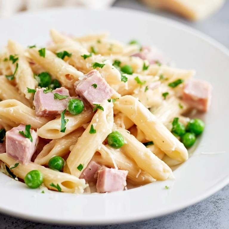 A close-up of Spring Pea & Ham Pasta shows rich, glossy sauce clinging to each perfectly cooked noodle.