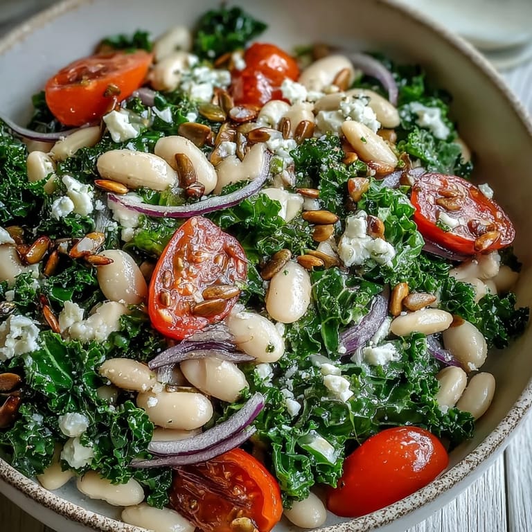 Hearty white bean and kale salad with tomatoes and seeds, tossed in dressing.