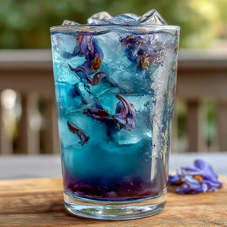 A stunning glass of butterfly pea flower lemonade, showcasing its enchanting blue-to-purple color shift, ideal for a cool, refreshing drink.