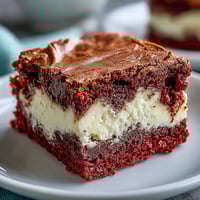 Freshly baked Red Velvet Cheesecake Brownies with rich cocoa swirls and creamy cheesecake marbling, cut into squares.