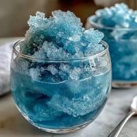 Blue Raspberry Lemonade Slushie in a frosty glass, garnished with lemon slices and fresh raspberries.